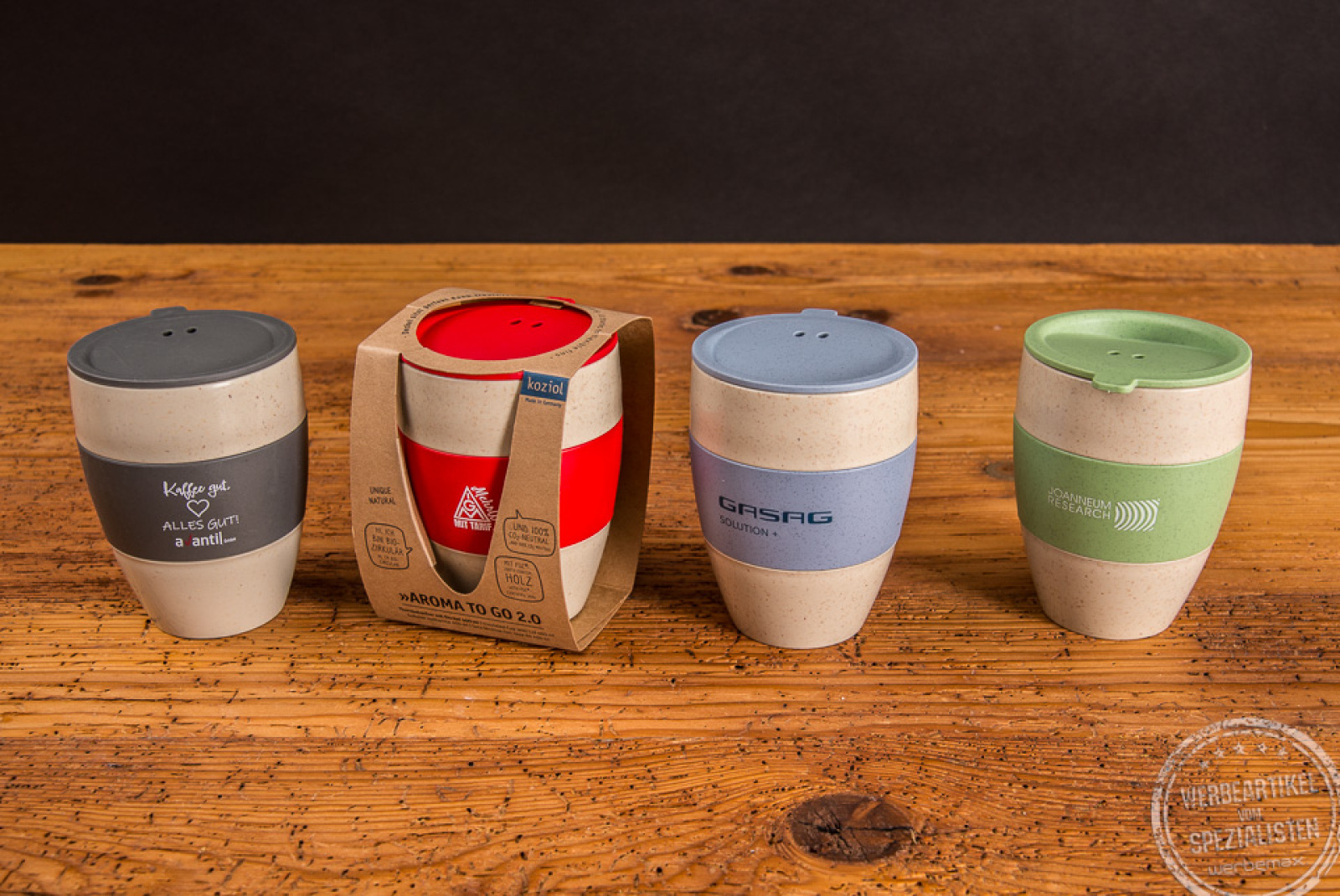 Vier Thermos Kaffeebecher Aroma to go mit unterschiedlichen Deckelfarben und unterschiedlichen Manschette als Werbeartikel.