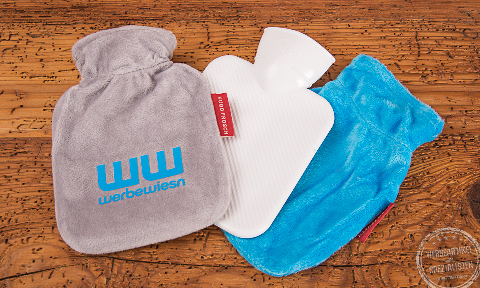 Drei W&auml;rmflaschen in grau, wei&szlig; und hellblau auf Holzplatte. 