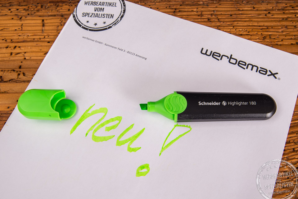 Textmarker von Schneider in Schwarz mit gr&uuml;ner Kappe. Auf wei&szlig;em Blatt Papier steht das Wort "Neu" in gr&uuml;n