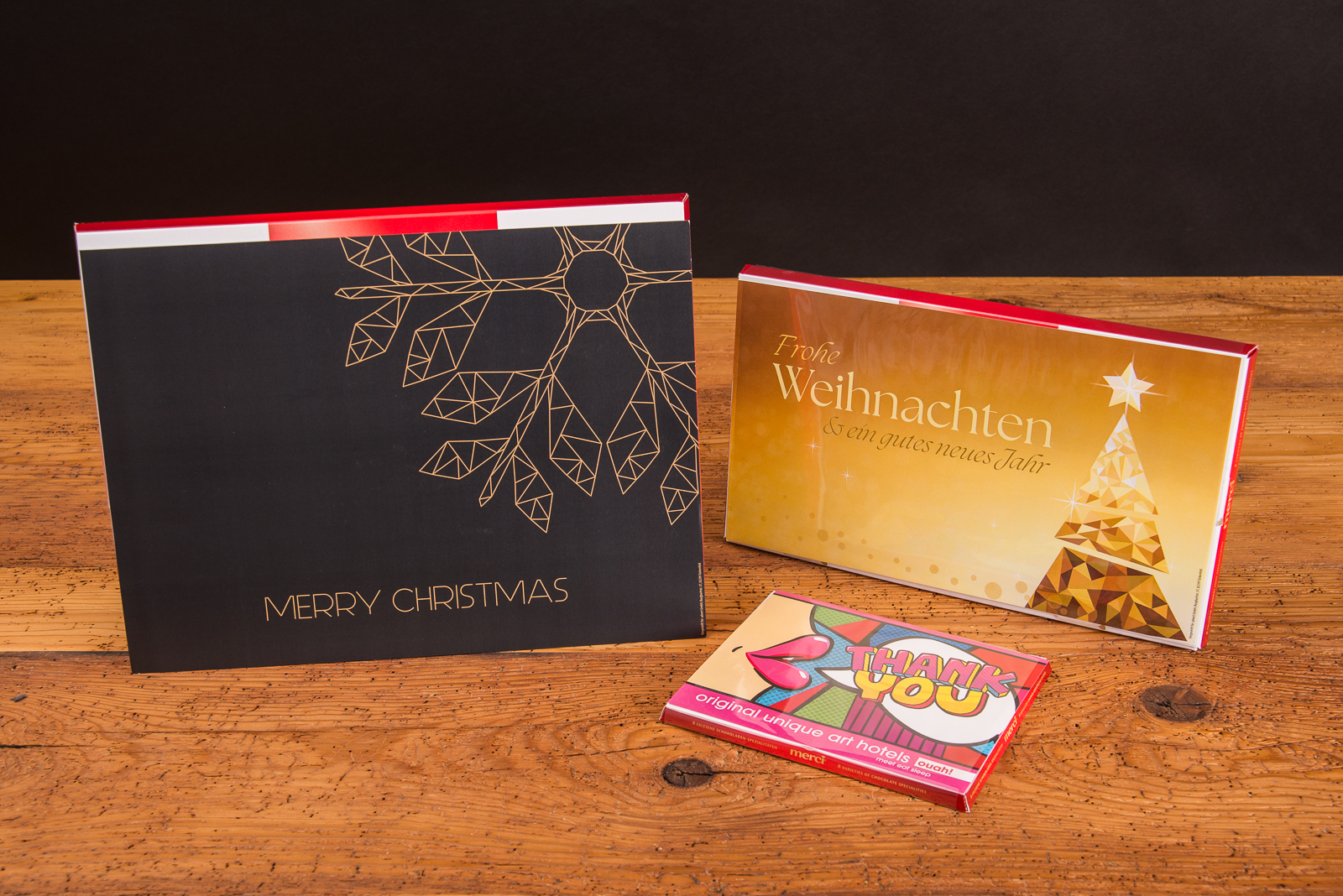 Storck Merci Finest Selection mit individuellen Gru&szlig;botschaften in verschiedenen Gr&ouml;&szlig;en  als give-away im Merchandise.. Die Schokoladenschachteln stehen senkrecht und man kann die weihnachtlichen Motive der 3 Beispiele gut erkennen.