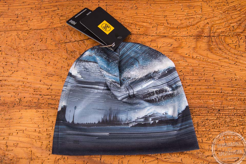 BUFF Ecostretch Beanie als Merchendise mit vollfl&auml;chigem Druck und Hangtag auf Holztischplatte