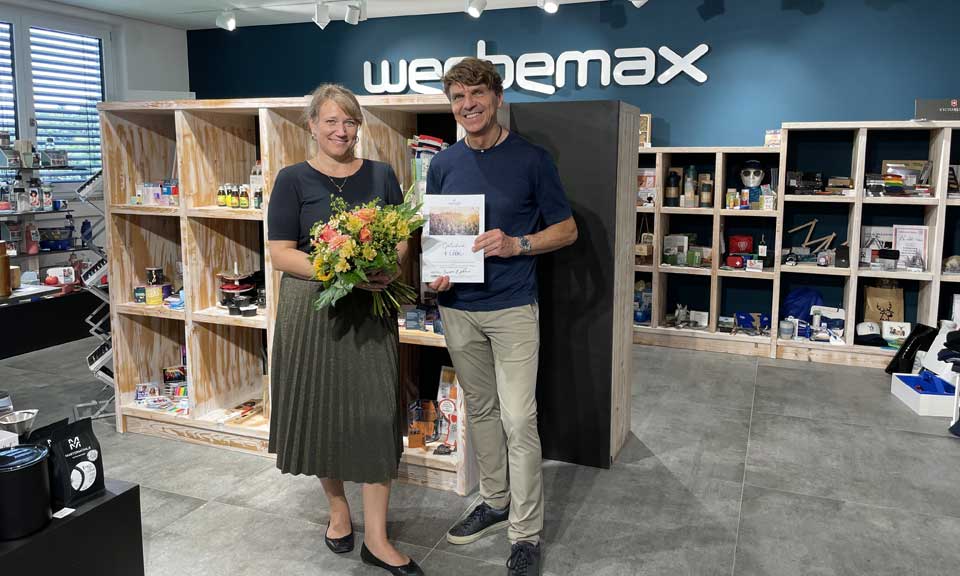Irina Belger mit Blumenstrau&szlig; in der Hand zusammen mit Gerhard Betzold im werbemax Showroom anl&auml;sslich Irinas Firmenjubil&auml;um.