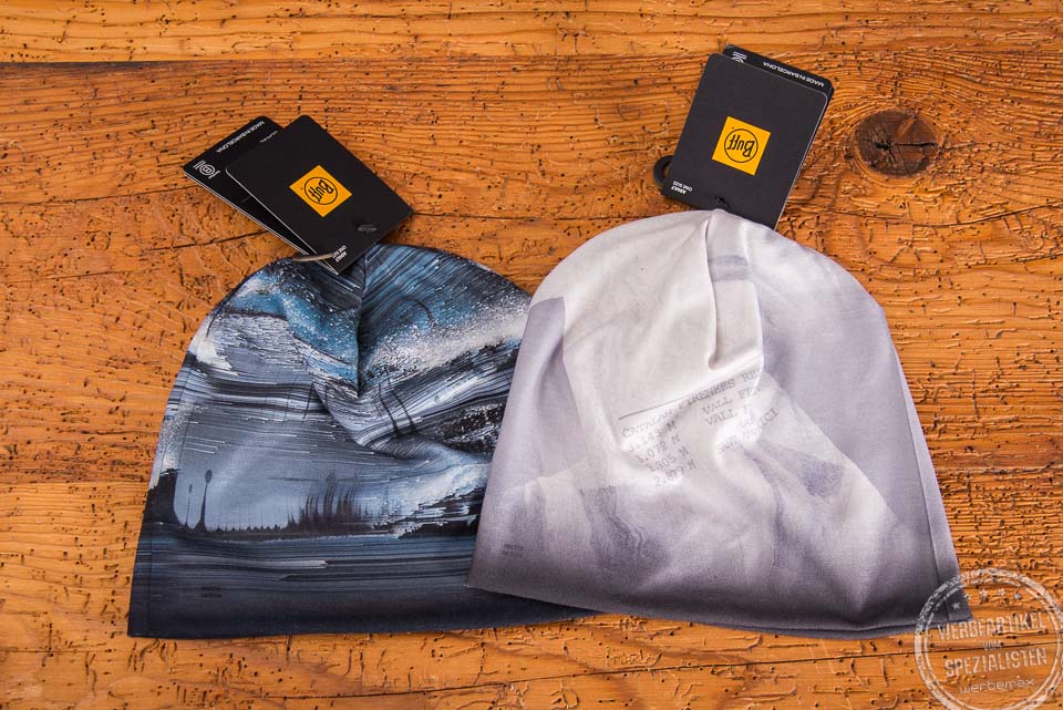 Zwei d&uuml;nne M&uuml;tzen von BUFF im 4c-Druck auf einem Holztisch gelegt mit dem original BUFF Label als Kundengeschenk