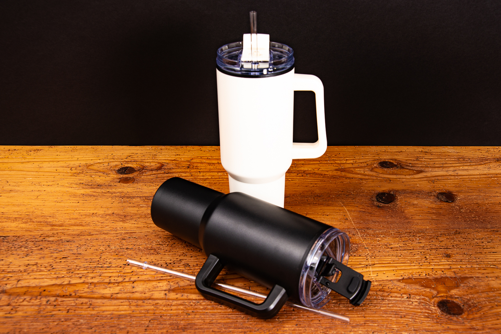 Ein stehender Tumbler creme und davor ein liegender Tumbler schwarz als Werbeartikel.