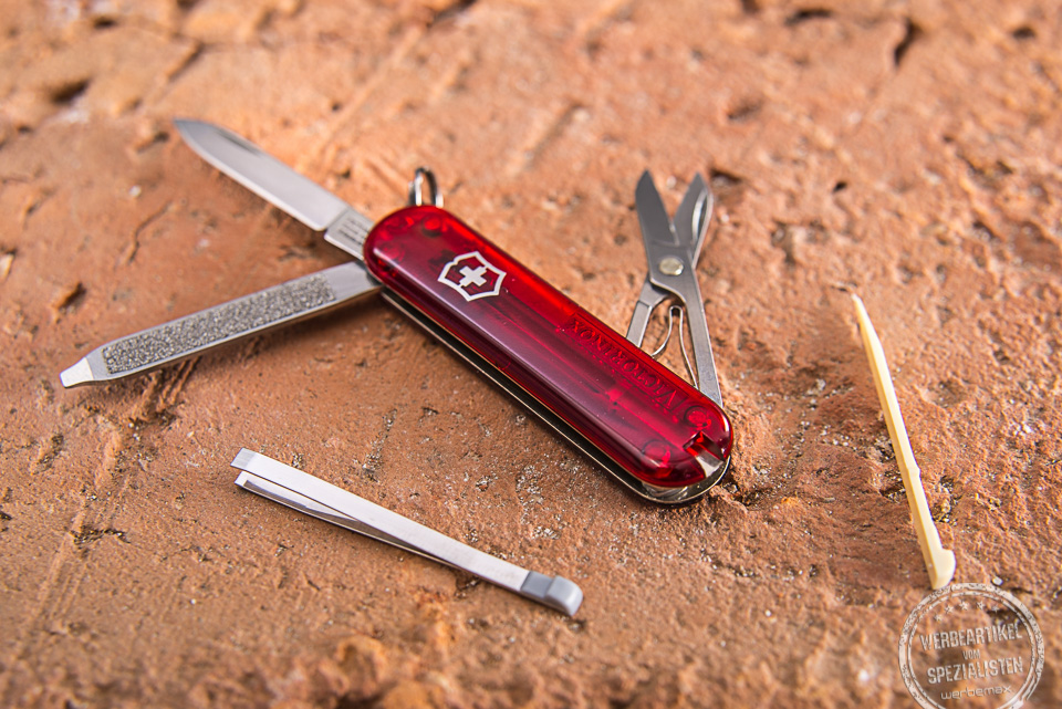 Das Schweizer Taschenmesser Victorinox Classic SD auseinandergebreitet auf einem Ziegelstein liegend als Werbeartikel.