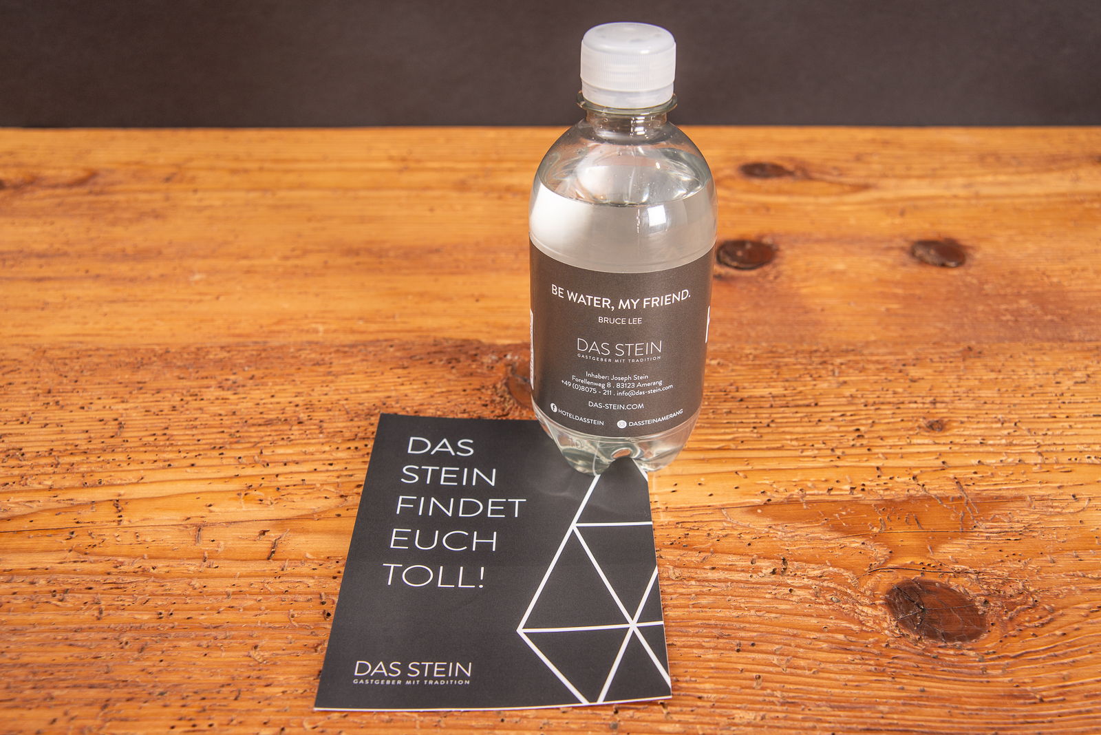 Eine Werbewasserflasche mit individuellem Etikett auf einer passenden Werbekarte stehend.