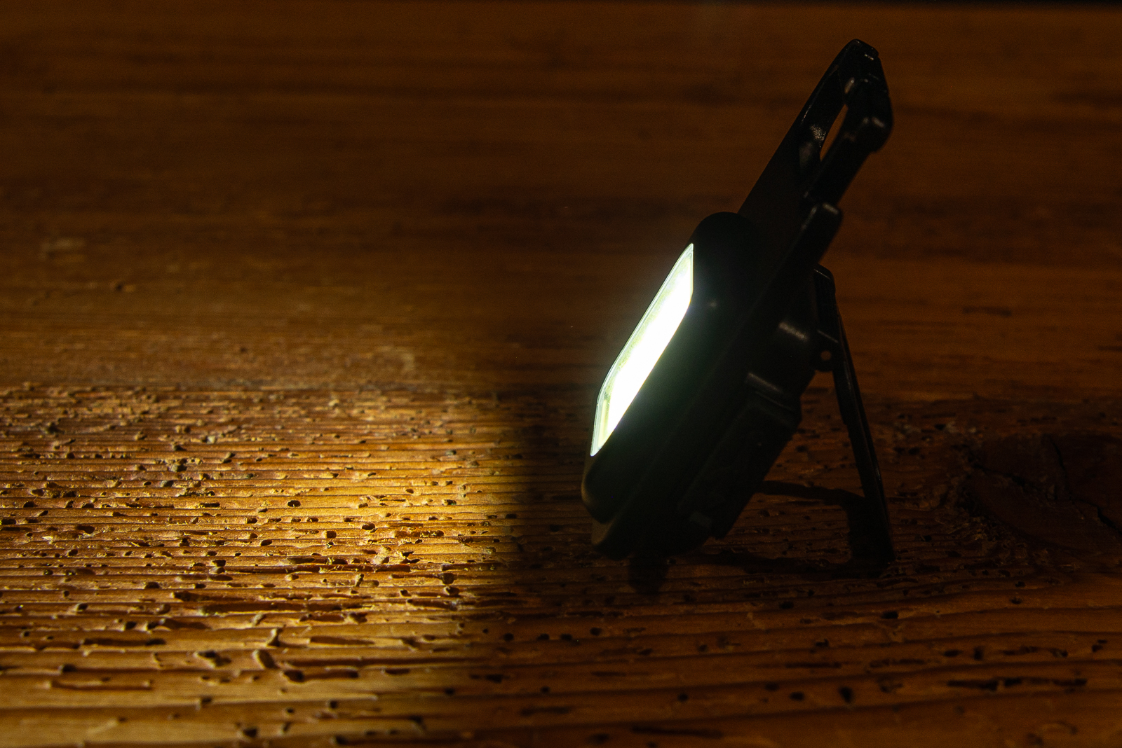 Ein Worklight, das im Dunkeln auf einer Holzplatte steht und leuchtet.