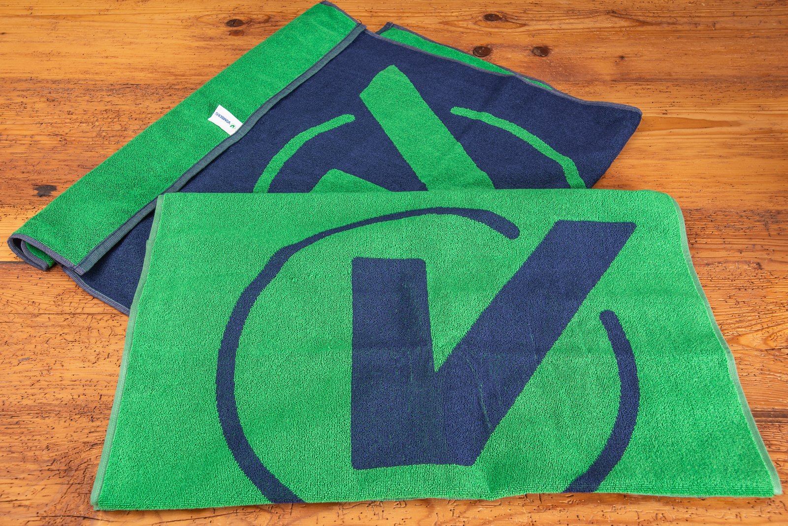 Zwei Strandt&uuml;cher in gr&uuml;n-blau mit Logo-Einwebung als hochwertiger Werbeartikel.