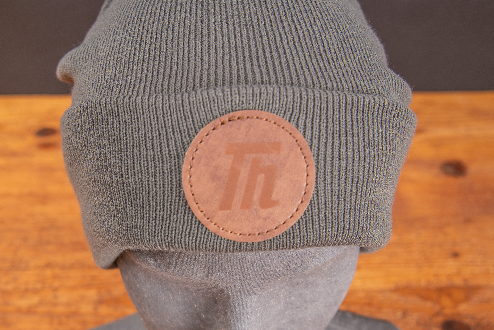 Graue Beanie mit runden PU-Patch als Werbeartikel.