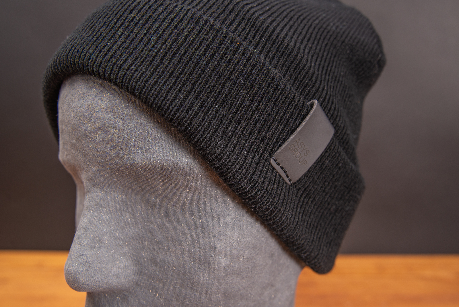 Schwarze Beanie mit schwarzem PU-Patch als Werbeartikel.