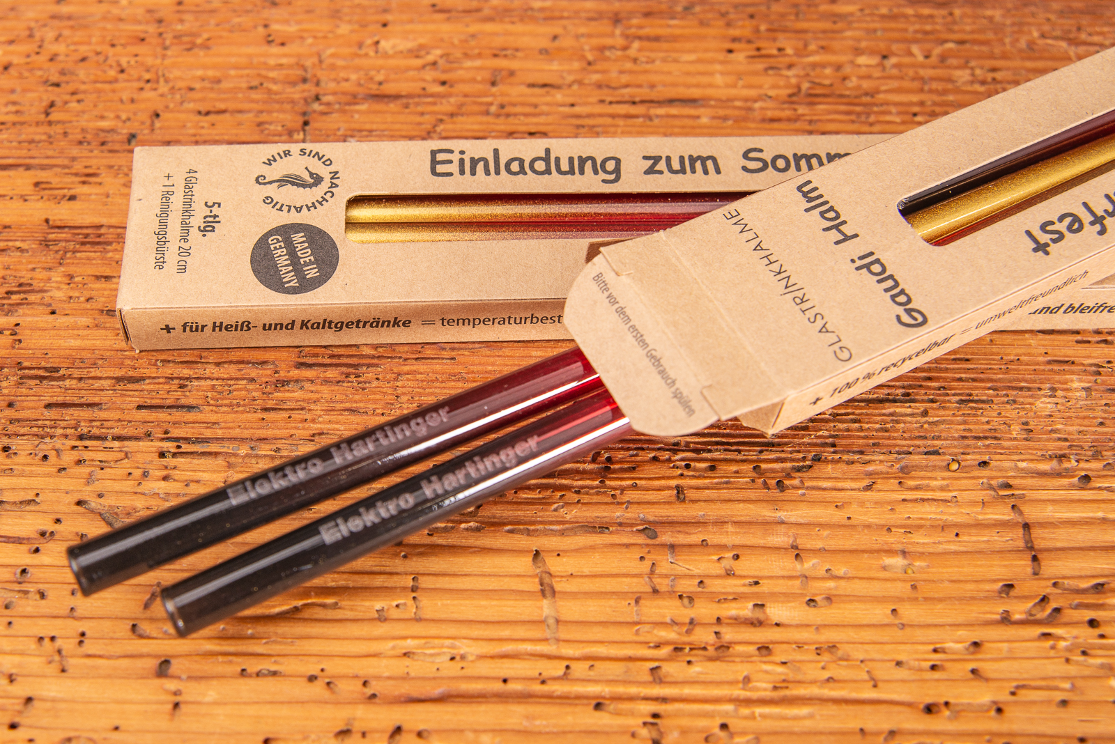 Zwei Werbekartonagen mit Deutschland-Glastrinkhalmen und einer Logogravur in Geschenkverpackung als Einladung.