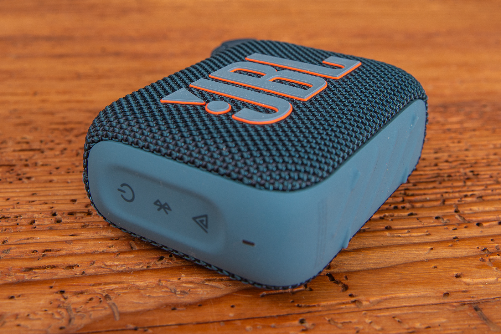 Blauer JBL GO 4 Bluetooth Speaker als Werbeartikel f&uuml;r Kunden und Mitarbeiter als Holztisch liegend..