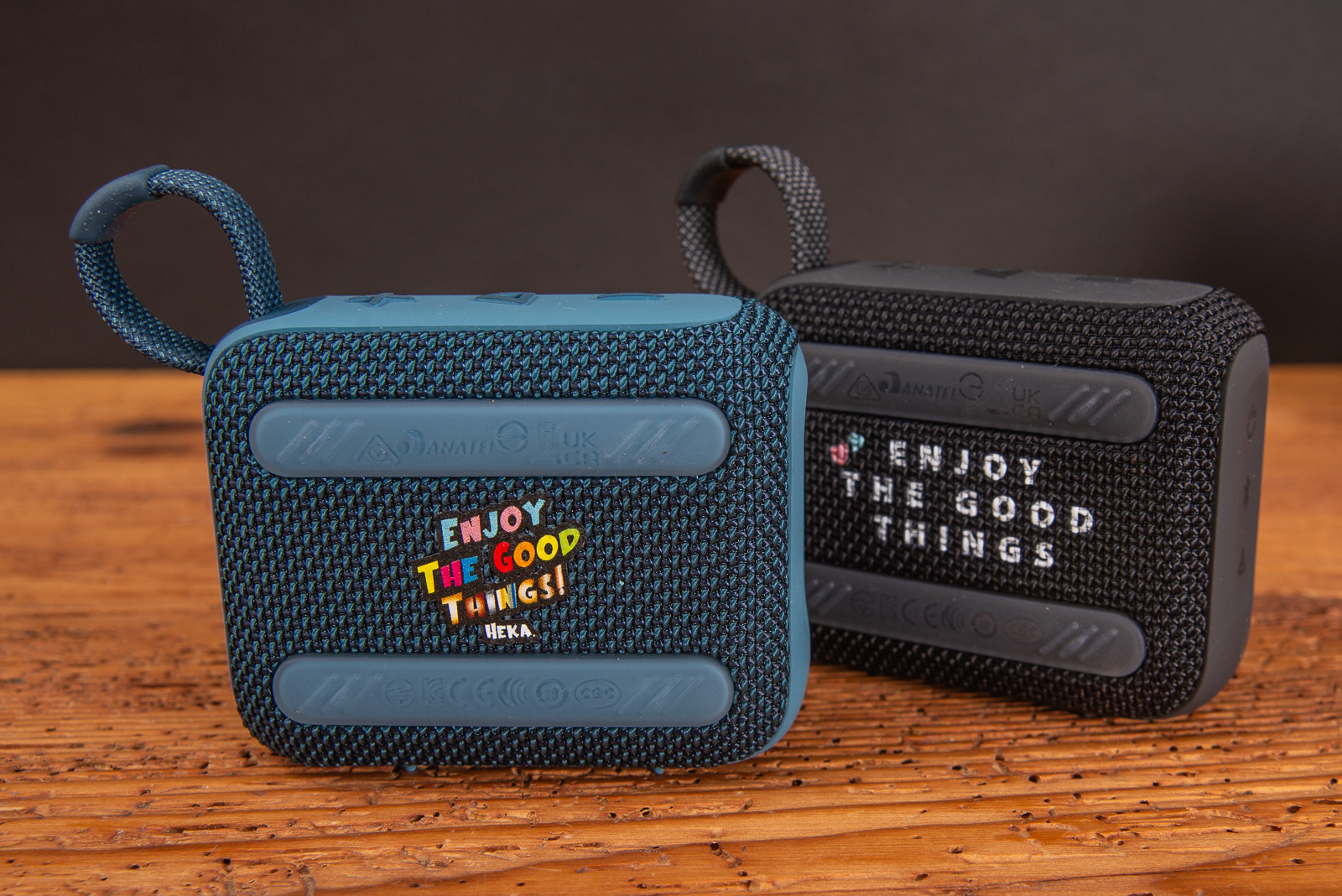 Zwei JBL GO 4 Bluetooth Speaker mit Logodruck als Merch auf Holztisch.