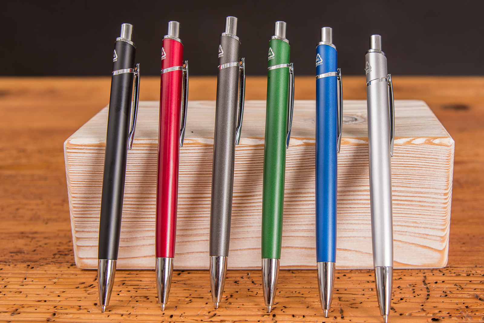&Uuml;bersicht der verschiedenen Farben von Parker Kugelschreibern mit Logo nebeneinander stehend an Holzblock gelehnt