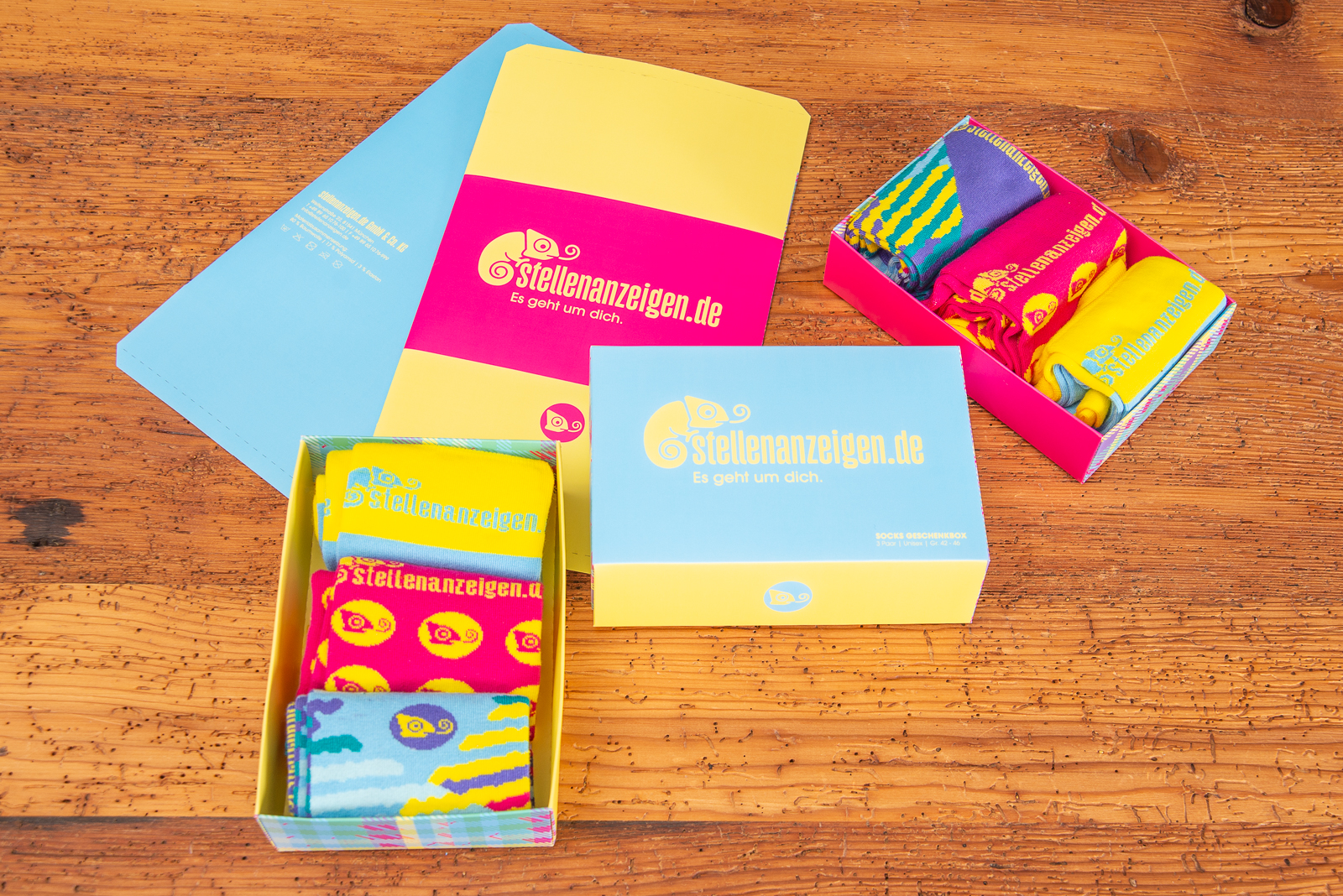 Knallig bunte Werbesocken in individuell gestalteter Werbe-Geschenkbox als Onboarding-Geschenk.