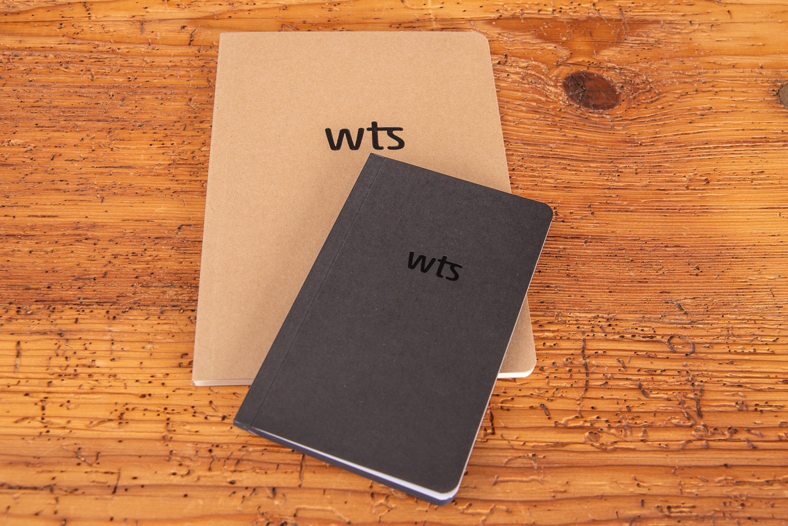 Braunes und schwarzes Notizbuch mit Logopr&auml;gung.