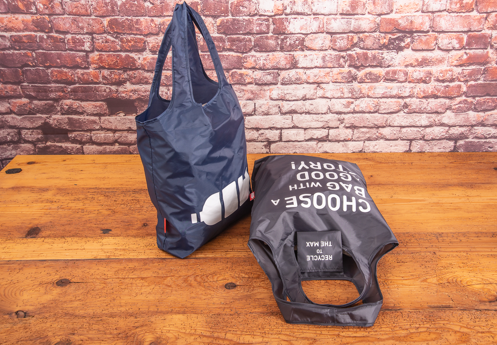 Faltbare, bedruckte Einkaufstasche aus 100% recycelten Plastikflaschen in blau und schwarz auf Holztisch