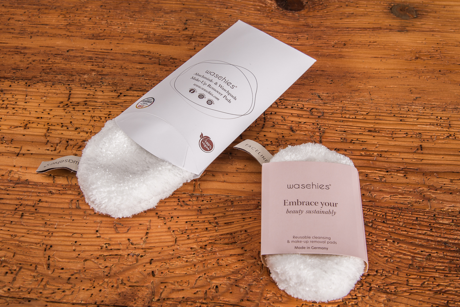 Zwei wiederverwendbare Abschminkpads Waschies mit bedruckter Kissenverpackung und Banderole als Werbeartikel.