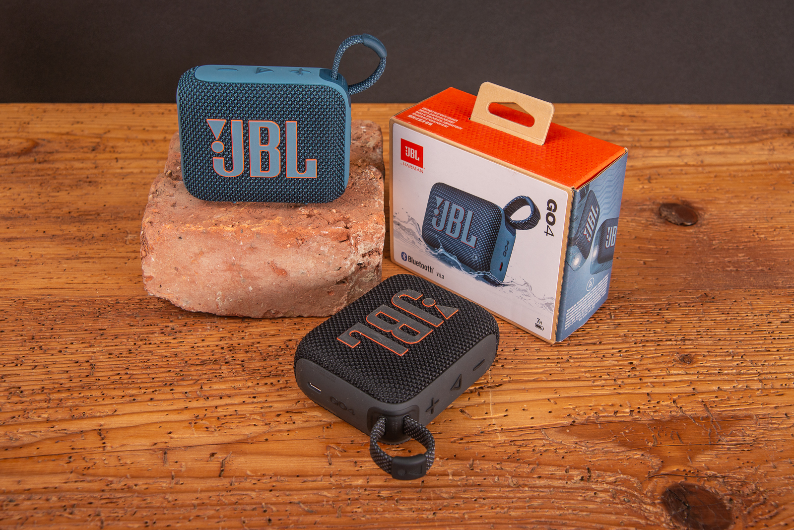 Zwei JBL GO 4 Bluetooth Speaker mit einer Verpackung auf Holztisch als Werbeartikel f&uuml;r Messen und Events.