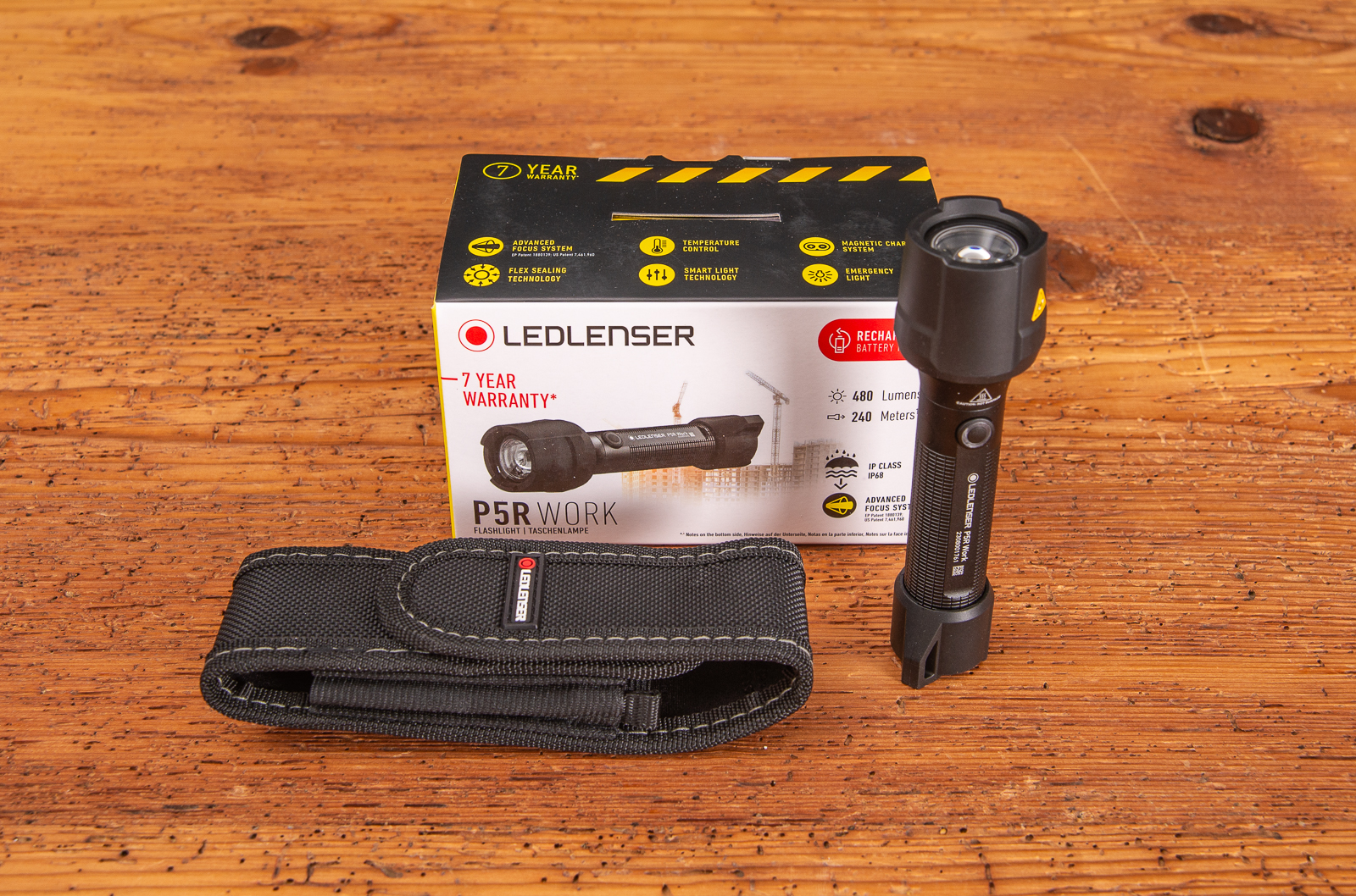 Professionelle LEDLenser P5R WORK Taschenlampe mit starker Leuchtkraft und G&uuml;rteltasche neben Geschenkverpackung als Marken Werbegeschenk auf Holztisch par&auml;sentiert.