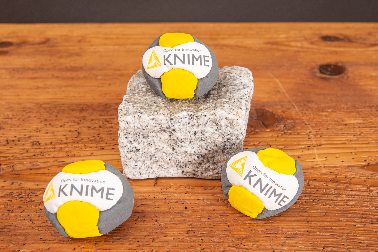 Drei Footbag mit Logodruck Knime als Werbeartikel auf Stein und Holtplatte.