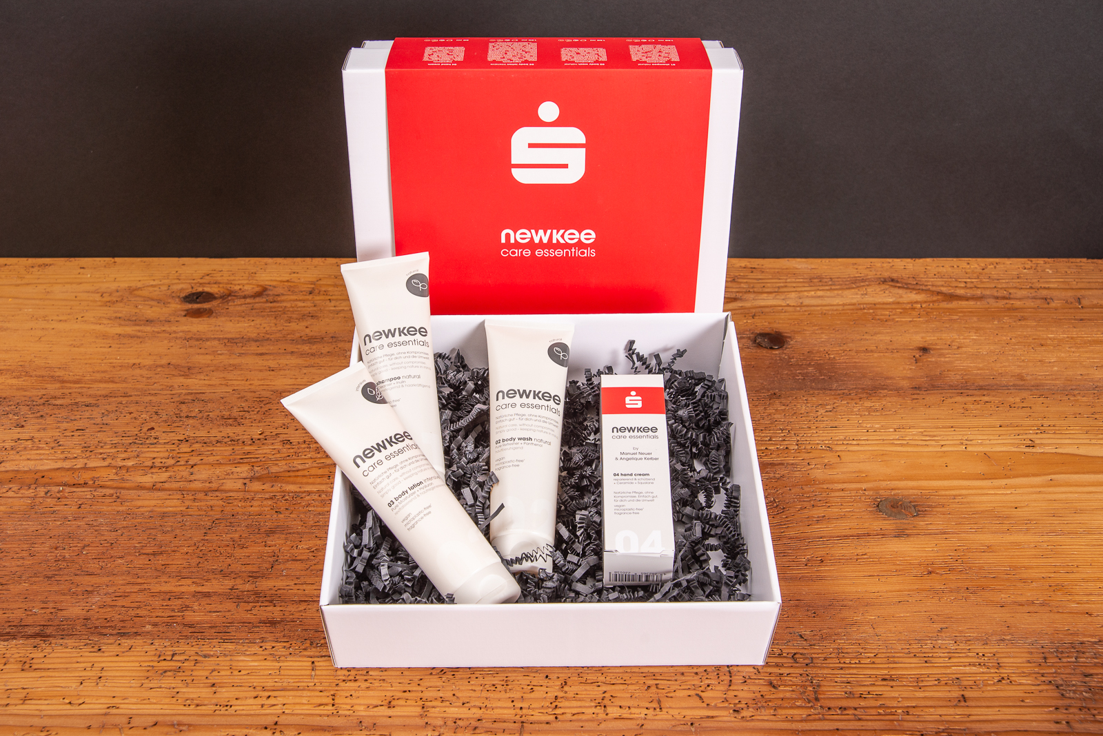 Newkee Pflegeset als hochwertiges Mitarbeitergeschenk mit Pflegeprodukten in stilvoller Geschenkbox mit Logo, ideal als nachhaltiges Werbegeschenk zu Weihnachten oder f&uuml;r besondere Anl&auml;sse im Unternehmen offen auf Holztisch