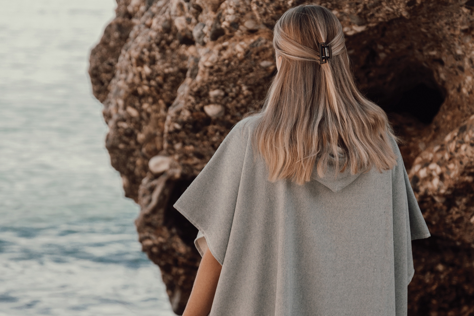 R&uuml;ckenansicht des Badeponcho in Grau. Mit Kapuze und Logoveredelung. 