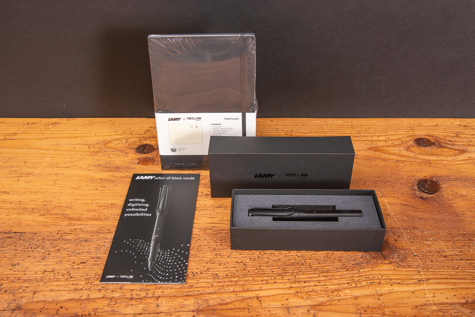 LAMY safari all black ncode Set mit Smart Pen und codiertem Notizbuch f&uuml;r digitales Schreiben auf Holztisch pr&auml;sentiert.