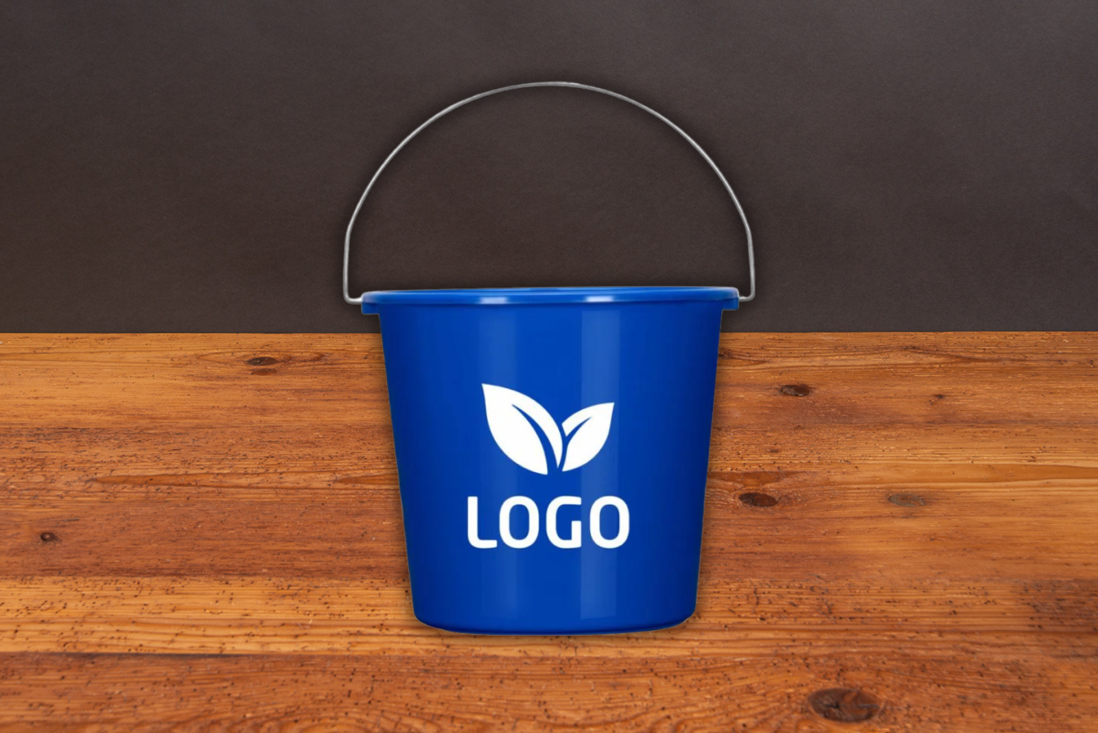 Werbeeimer als Messetasche oder Werbegeschenk auf Festivals mit Ihrem Logo. Hier in einem sch&ouml;nen Blau mit einem wei&szlig;en Aufdruck zu sehen auf Holztisch. 