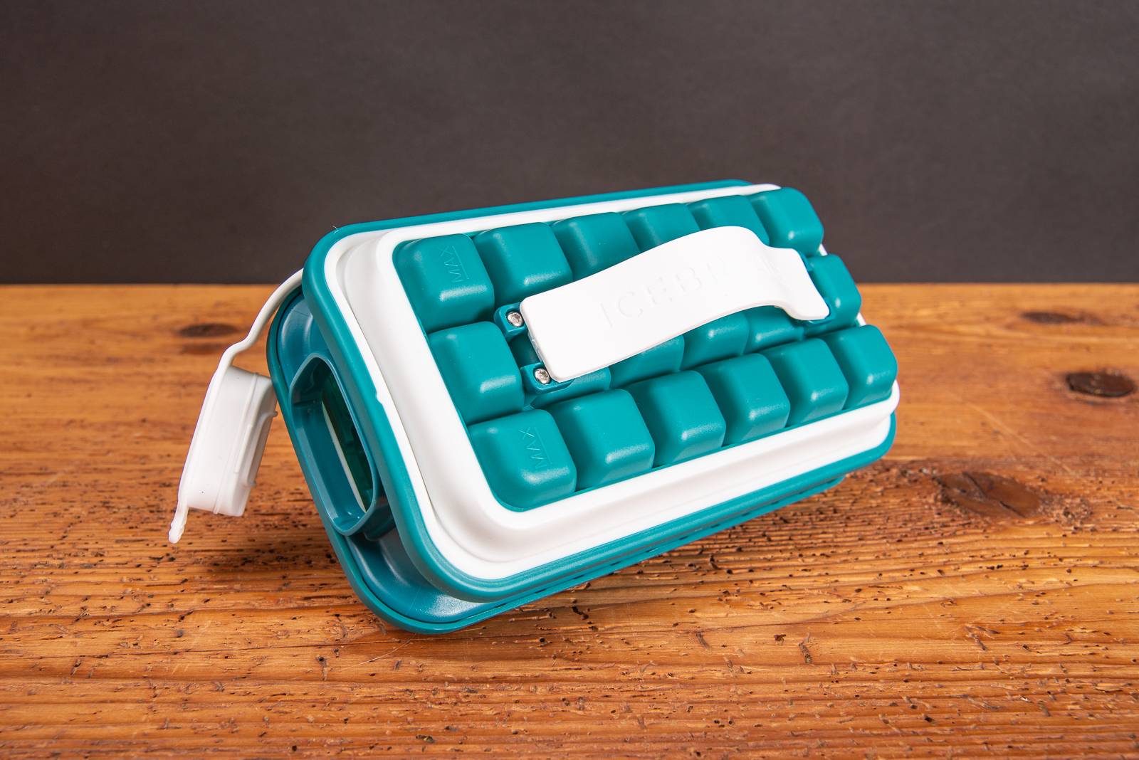 Moderner Eisw&uuml;rfelbeh&auml;lter IceBreaker&reg; Pop in leuchtendem T&uuml;rkis als cooles Incentiv mit ge&ouml;ffnetem Deckel auf Holztisch 