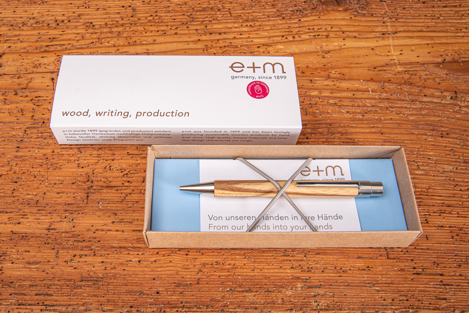 Nachhaltiger Holzkugelschreiber VIVO aus hochwertigem Holz mit Messingspitze und Logodruck in offener Geschenkverpackung auf Holztisch
