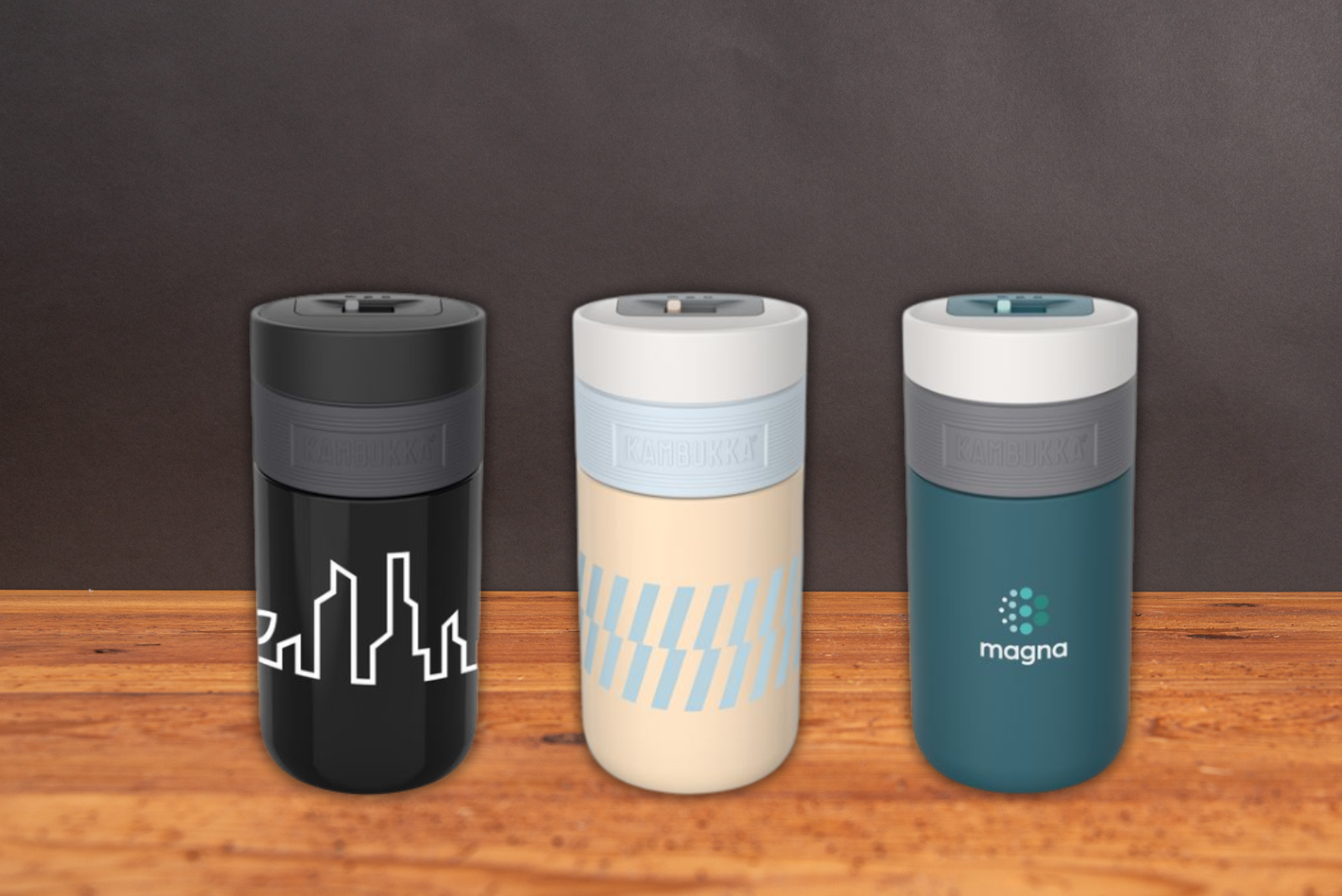 Kambukka Etna Thermobecher in den Farben schwarz, deep teal, iced latte mit 300ml Volumen und einem praktischen 3-in-1 Verschluss mit Logo gravieren lassen als hochwertiges Incentiv f&uuml;r Kunden und Mitarbeiter auf Holztisch.