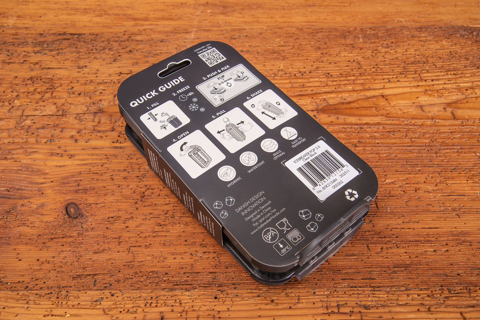 Banderole derEisw&uuml;rfelbox Icebreaker Pop in schwarz mit Beschreibung auf Holztisch liegend