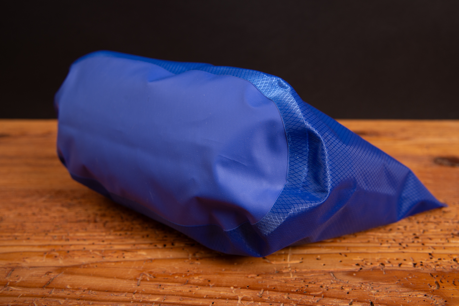 Liegend fotografierte gef&uuml;llte Halfar Drybag 3L in Royalblau auf Holztisch.