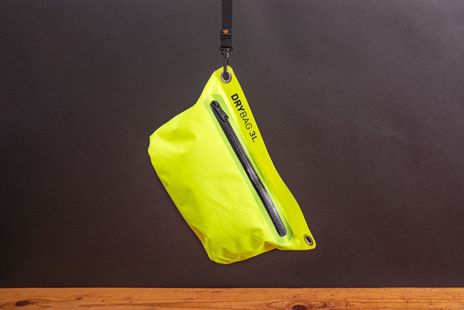 Wasserdichte Drybag 3L von Halfar in Neongelb mit H&auml;ngeschlaufe vor dunklem Hintergrund als Werbegeschenk.