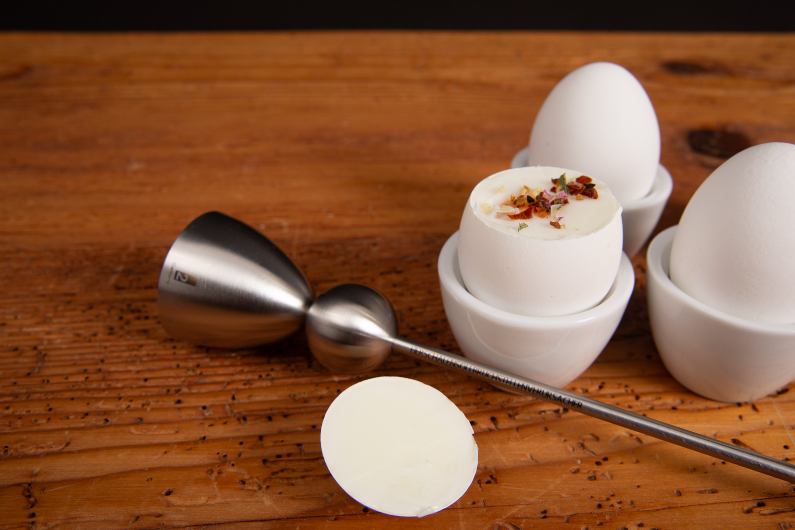 Detailaufnahme des Clack Eier&ouml;ffners nach der Anwendung &ndash; ge&ouml;ffnetes Fr&uuml;hst&uuml;cksei mit Kr&auml;utern serviert.