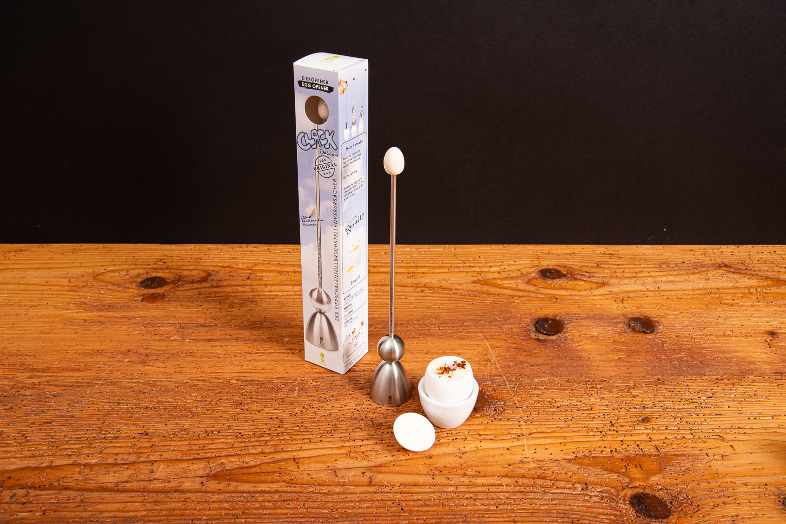 Clack Eier&ouml;ffner aus Edelstahl mit Verpackung und ge&ouml;ffnetem Ei im Becher &ndash; hochwertiges K&uuml;chenaccessoire.