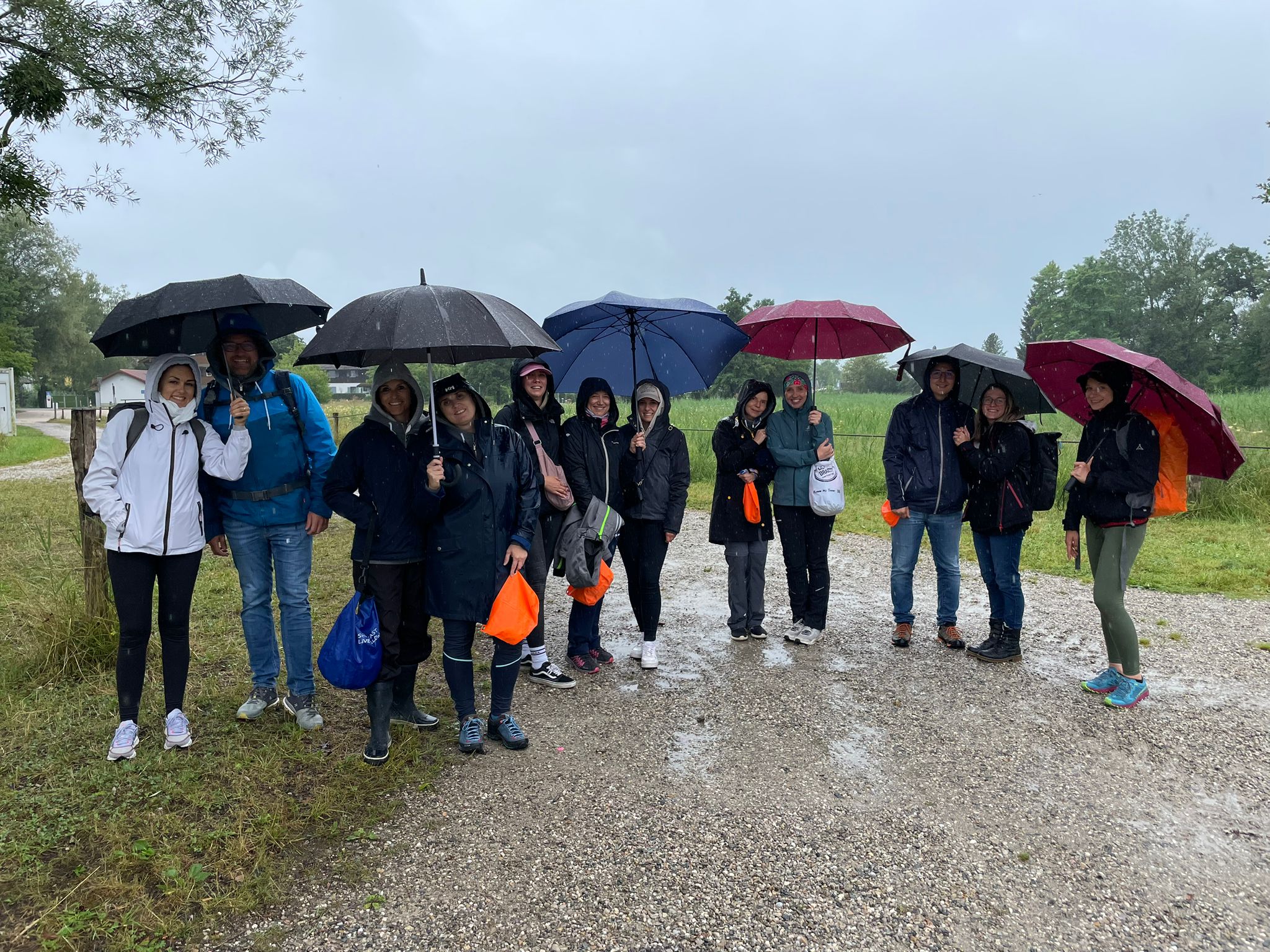 Das werbemax Team im Regen mit Regenschirmen vor Beginn der Alz Flo&szlig;fahrt.