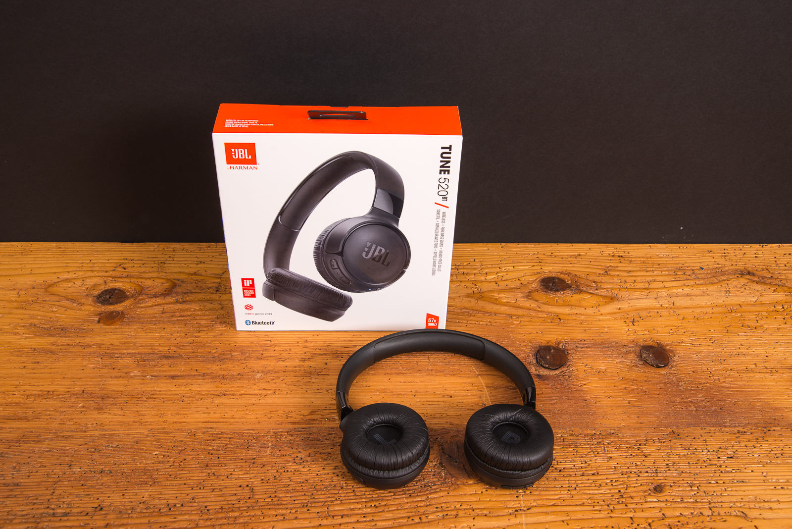 JBL Tune 520BT Bluetooth Kopfh&ouml;rer in Schwarz vor Originalverpackung auf Holztisch als trendiger Werbeartikel f&uuml;r gesch&auml;tzte Kunden und Mitarbeiter