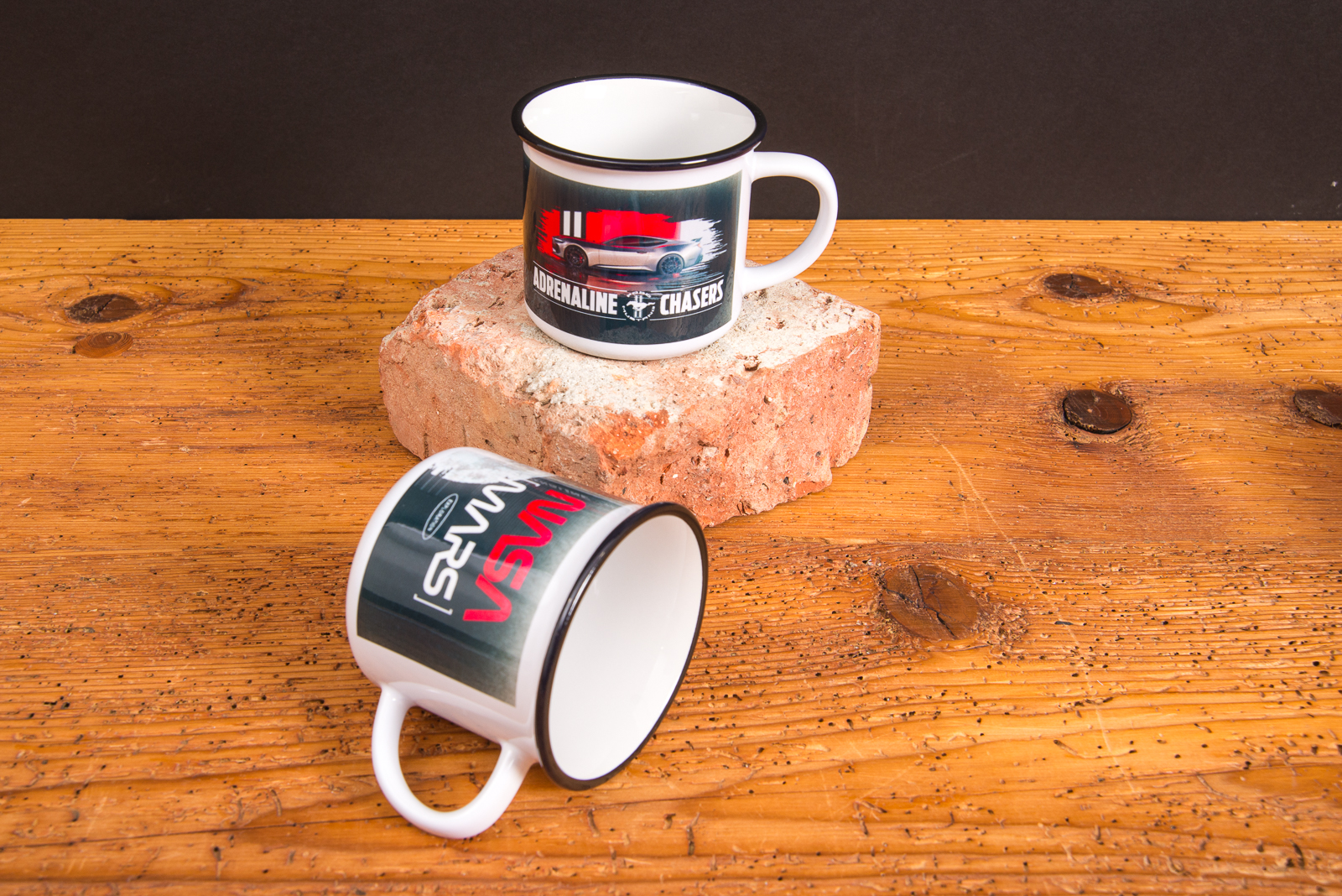 Zwei Keramik-Tassen mit sportlichem Motiv &bdquo;Adrenaline Chasers&ldquo; &ndash; hochwertige bedruckte Werbeartikel Tassen im Retro-Look auf Backstein.