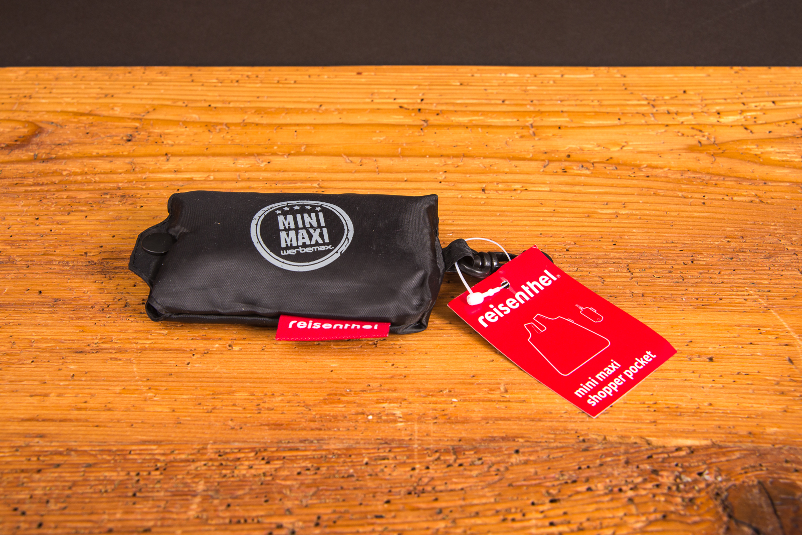 Kompakt verpackter reisenthel Mini Maxi Shopper Pocket in Schwarz mit Logo &ndash; praktische faltbare Tasche als Werbegeschenk bei werbemax.