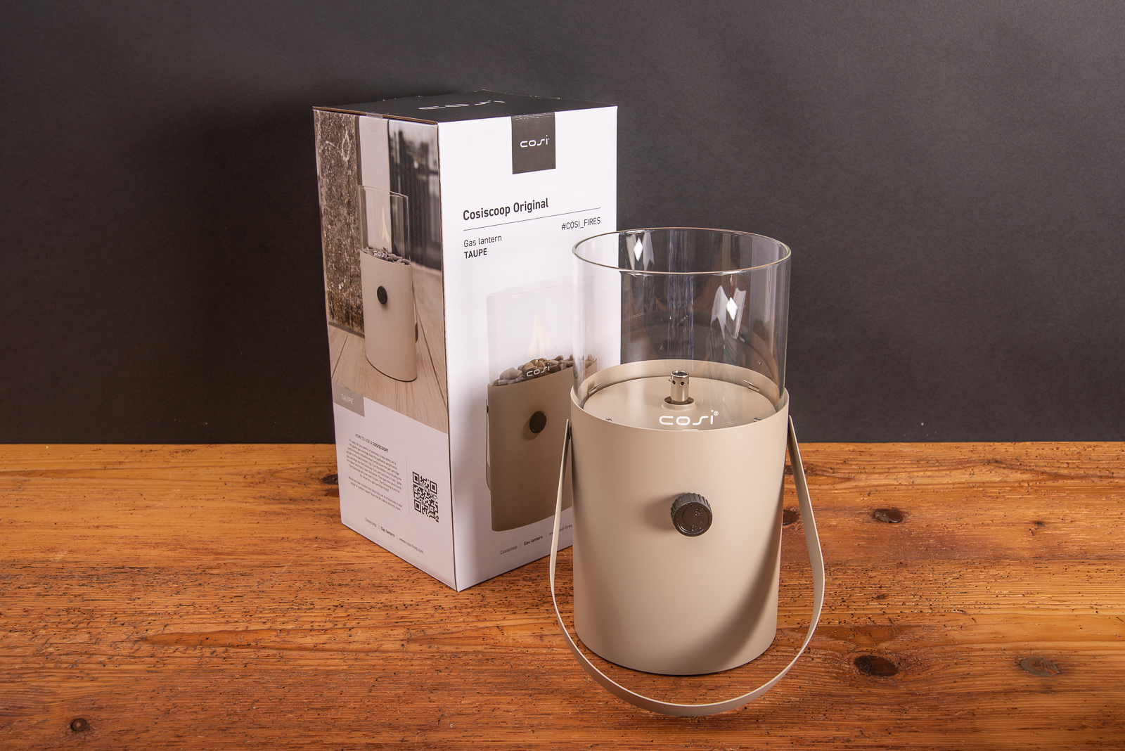 Cosiscoop Original Gaslaterne in Beige mit Verpackung auf Holztisch als hochwertiges Werbegeschenk mit Logogrvur.