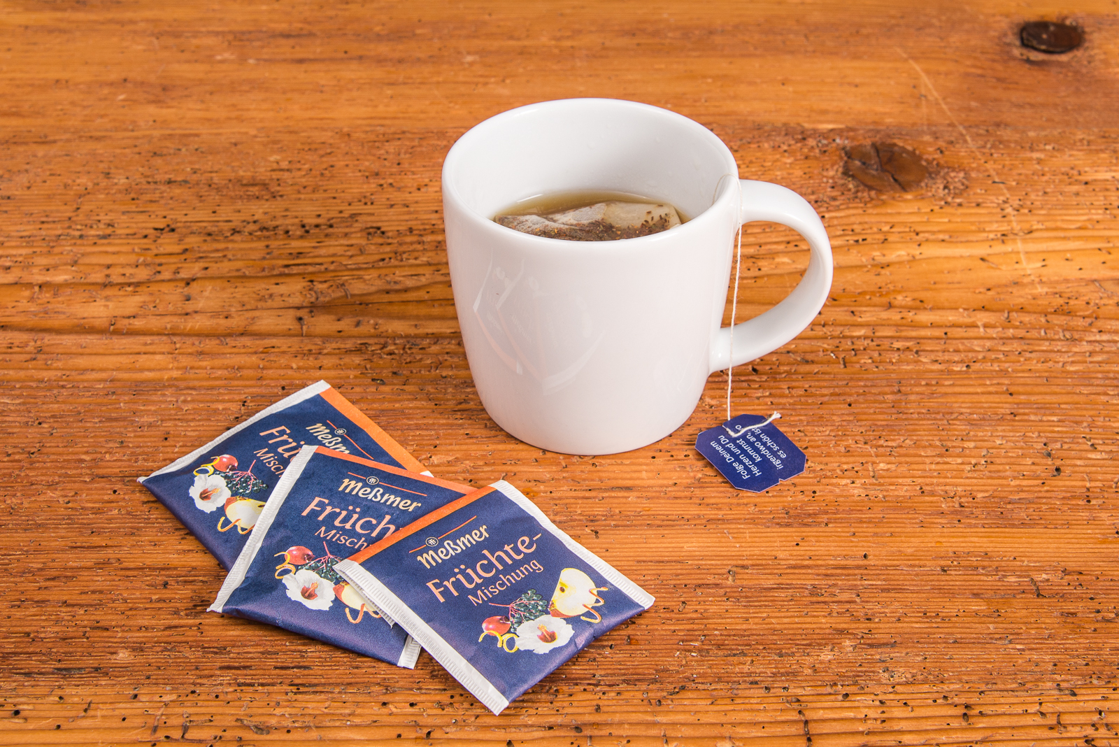 SND Porzellan Tasse mit Tee von Me&szlig;mer, Teebeutel und Verpackung daneben als perfektes Werbegeschenk