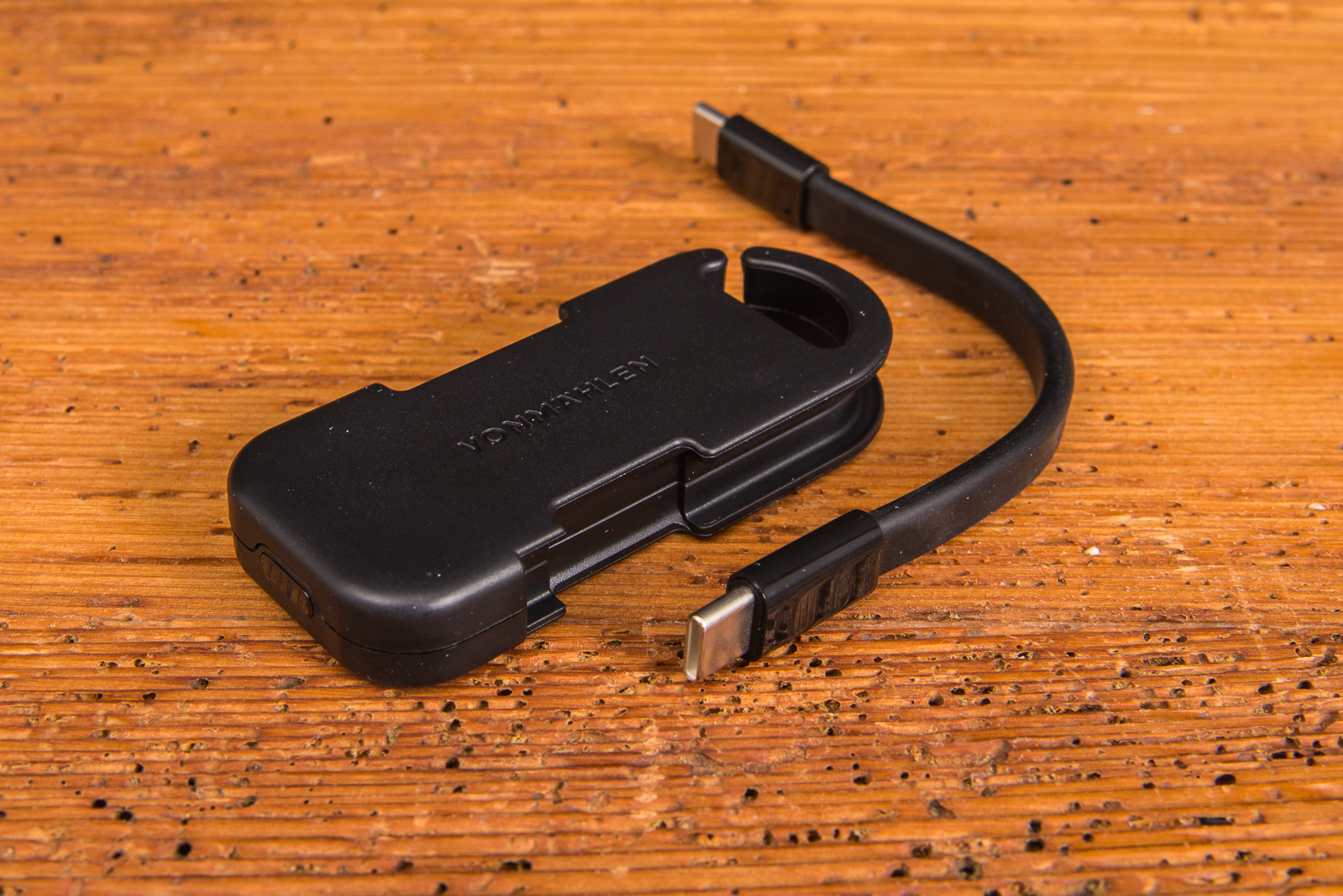 Vonm&auml;hlen Evergreen Go Powerbank in Schwarz mit abnehmbarem USB-C Ladekabel auf Holztisch.