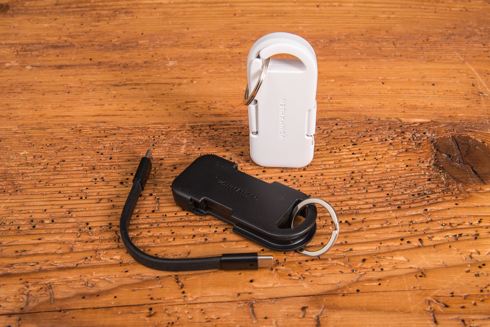 Vonm&auml;hlen Evergreen Go Powerbank in Wei&szlig; und Schwarz mit Schl&uuml;sselring auf Holztisch.