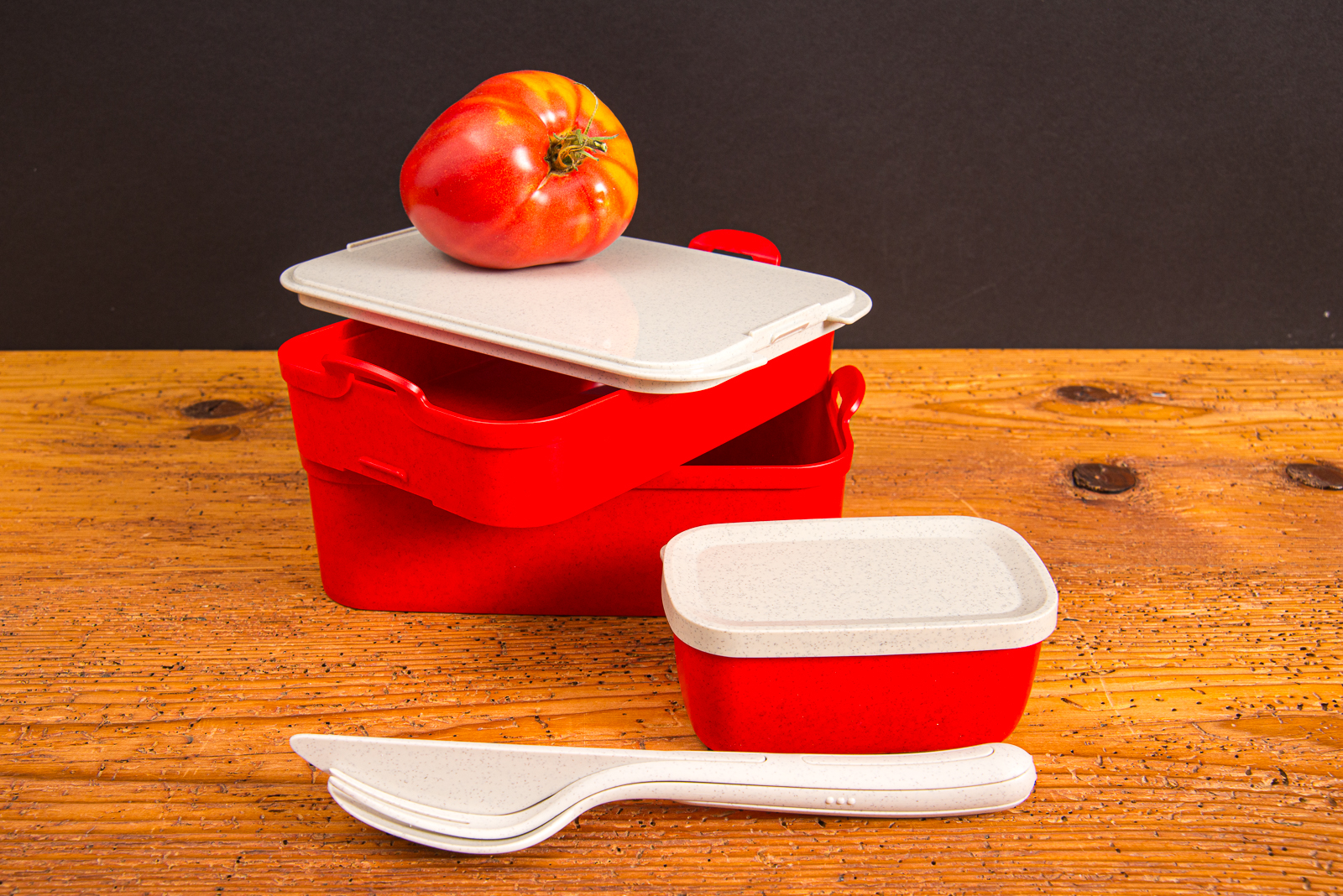 Rote Koziol Stakk Lunchbox mit Besteck und Apfel als hochwertiges Incentive mit Logo auf Holztisch