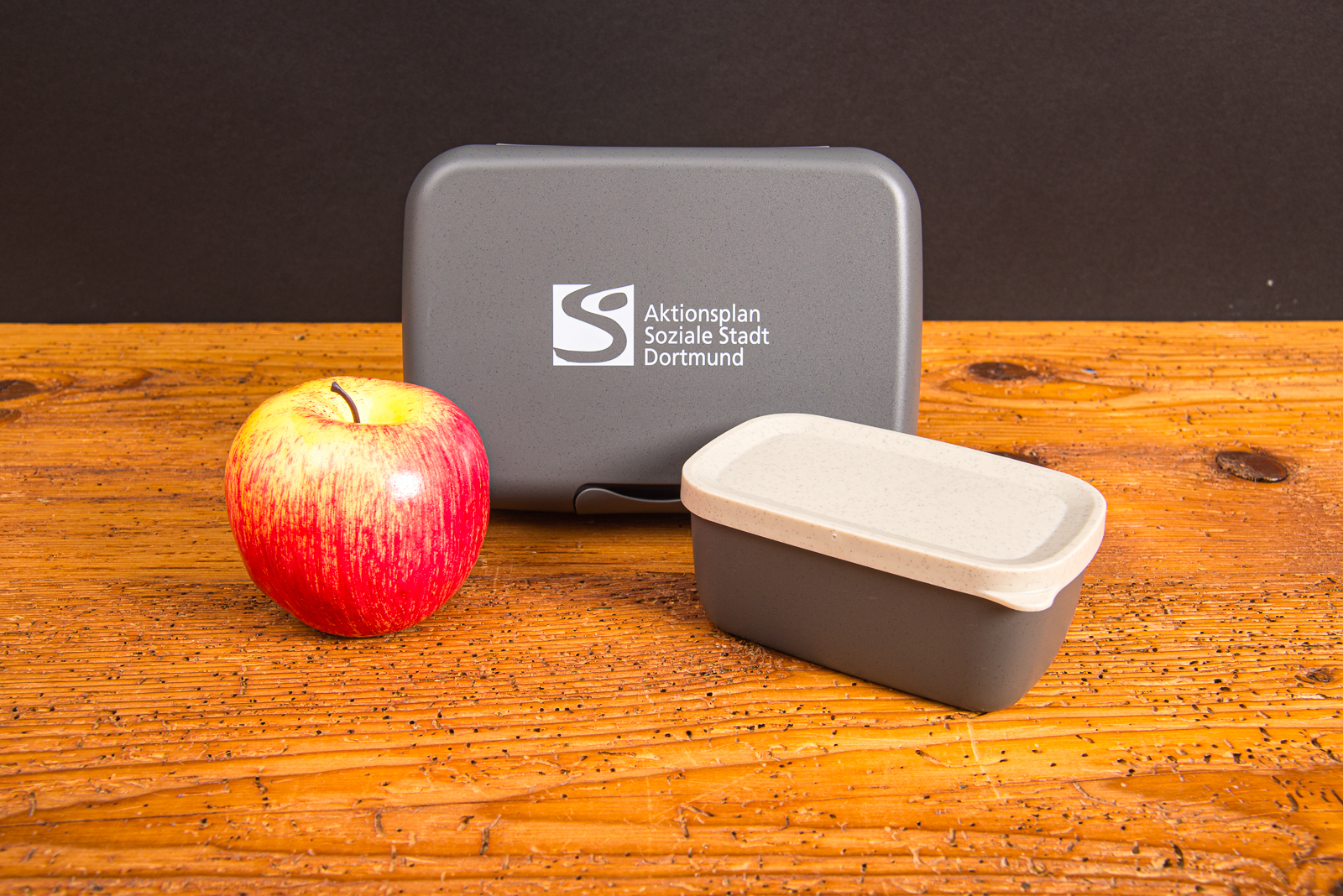 koziol Lunchbox Candy L mit individuellem Logo-Druck als nachhaltiges Merch Made in Germany, mit Apfel auf Holztisch f&uuml;r Onboarding oder Geburtstag von Mitarbeiter