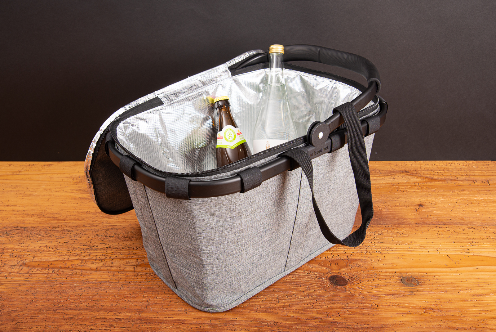 Reisenthel coolerbag mit Isolierfunktion im reisenthel Einkaufskorb in twist silver, gef&uuml;llt mit Getr&auml;nkeflaschen als hochwertiges und stilvolles Mitarbeitergeschenk auf Holztisch.