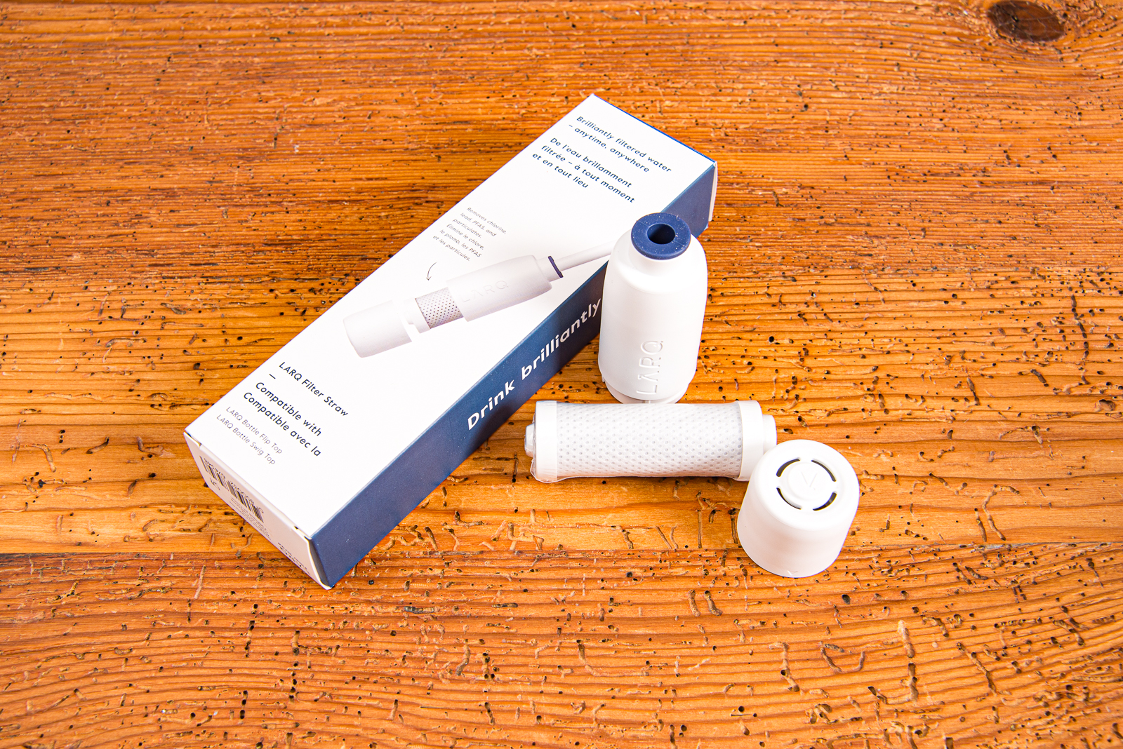 Detailbild des wei&szlig;en Larq Wasserfilters der alle 2 Monate selbstst&auml;ndig ohne Werkzeug ausgetauscht werden kann auf Holztisch liegend.