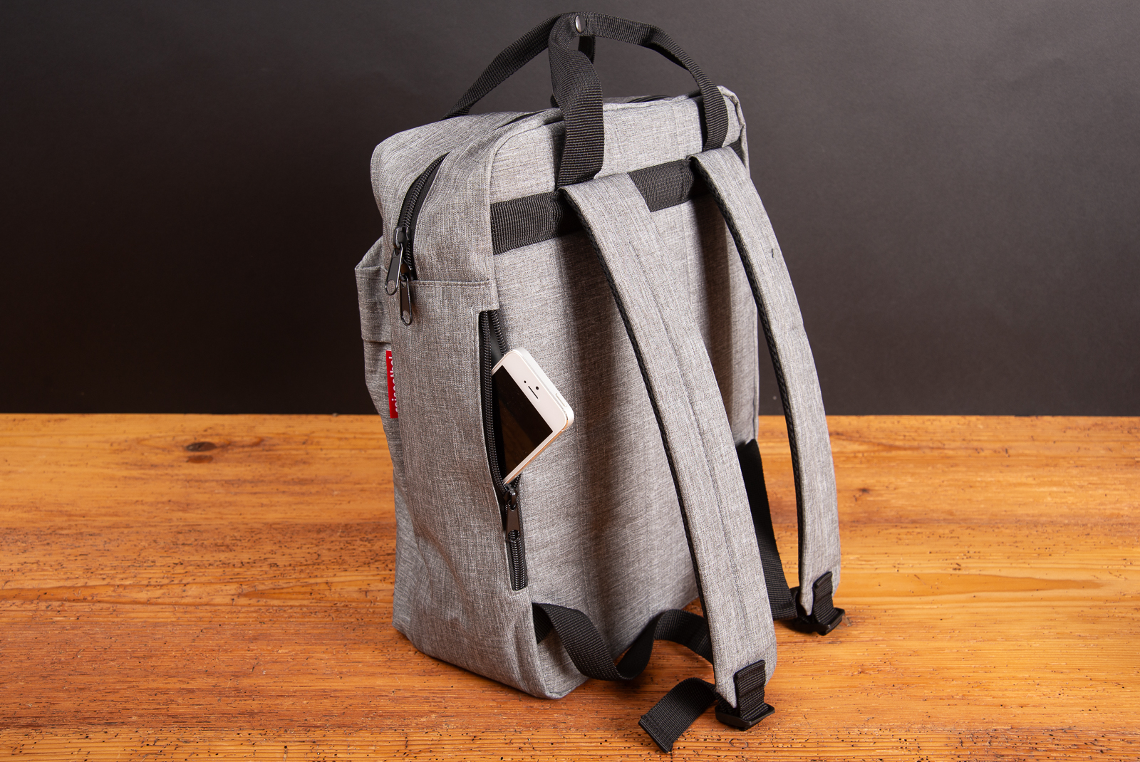 R&uuml;ckansicht des Reisenthel Allday Backpack Twist Silver in Grau mit Smartphone im Rei&szlig;verschlussfach &ndash; moderner, funktionaler Rucksack aus recyceltem Material als nachhaltiges Werbegeschenk oder Mitarbeiterpr&auml;sent.